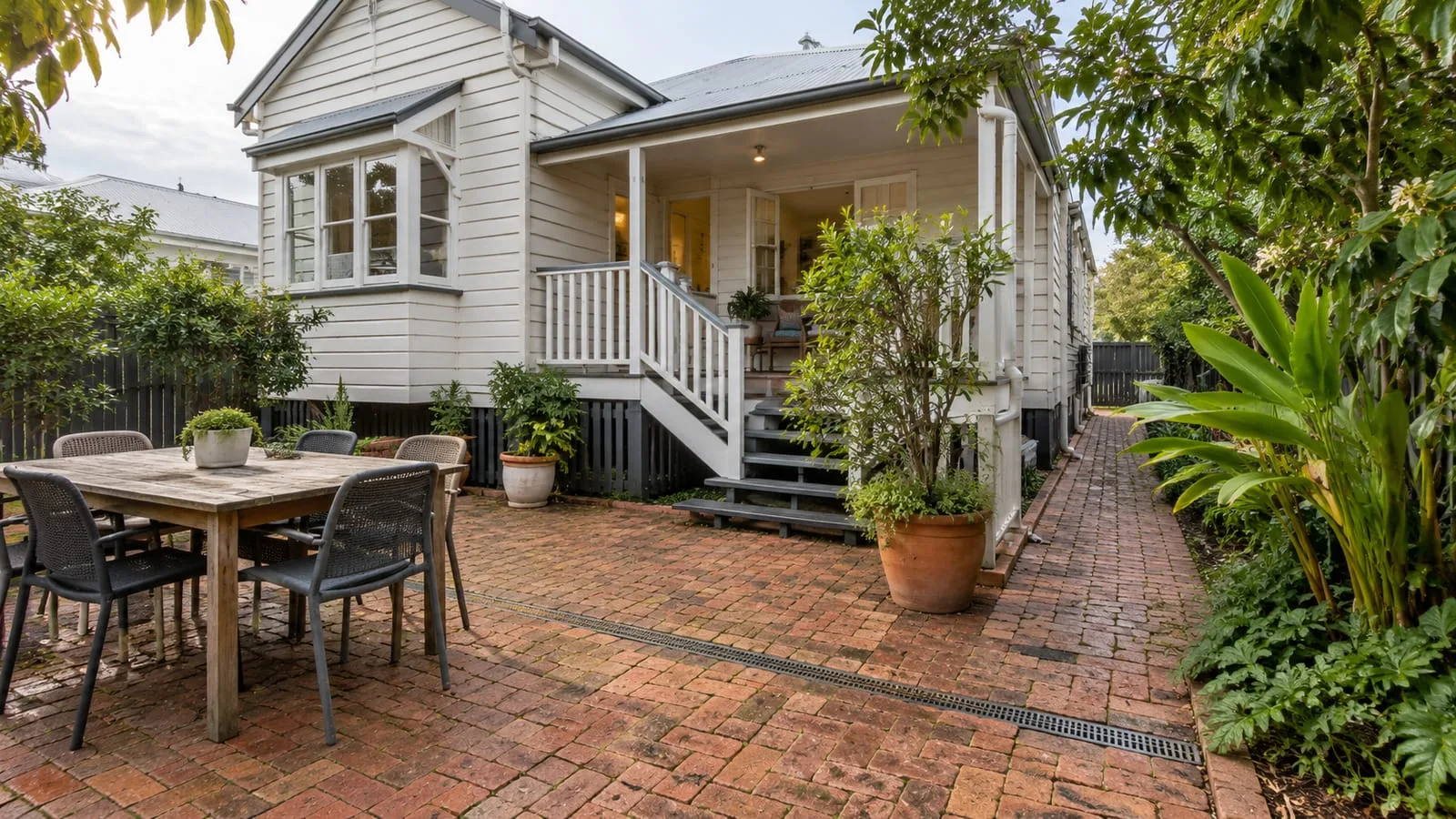 AI-generated illustration: South Brisbane older timber cottage with brick garden paving and a discreet surface drain